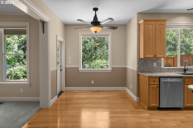 kitchen featuring light hardwood / wood-style flooring, stainless steel dishwasher, ceiling fan, backsplash, and sink