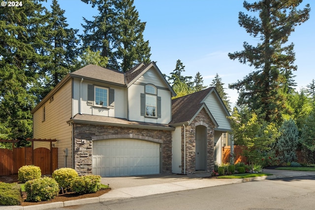 english style home with stone siding, an attached garage, fence, and driveway