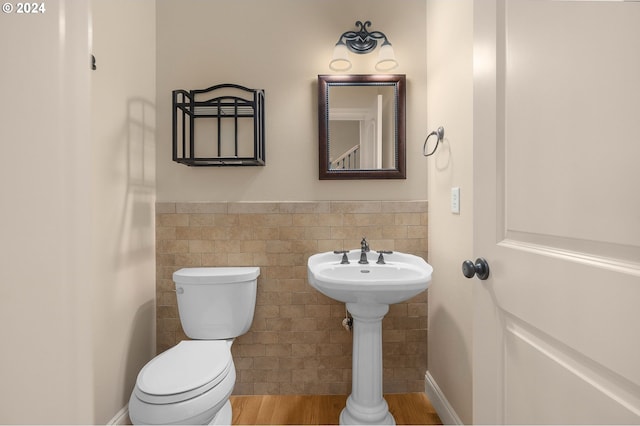 half bathroom with a wainscoted wall, tile walls, and toilet