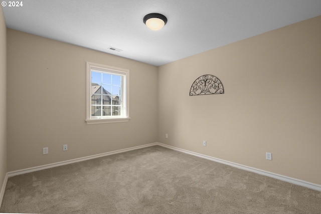 carpeted empty room featuring visible vents and baseboards