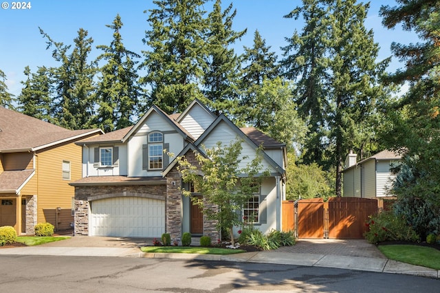 view of front of home featuring a gate, fence, a garage, stone siding, and driveway