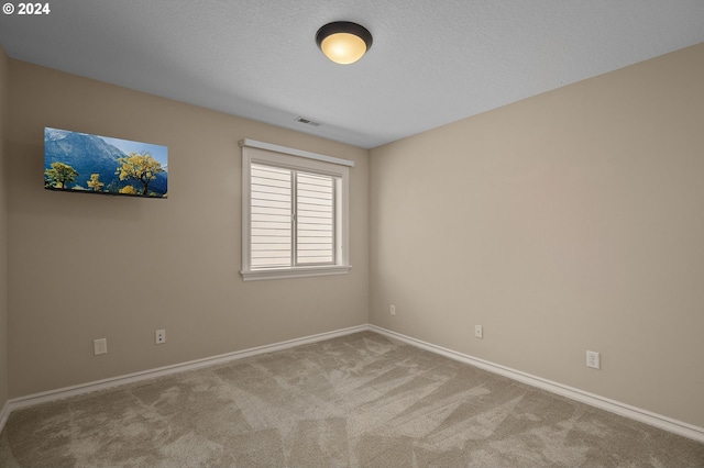 unfurnished room with carpet floors, visible vents, a textured ceiling, and baseboards