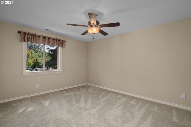 empty room featuring carpet floors, visible vents, ceiling fan, and baseboards