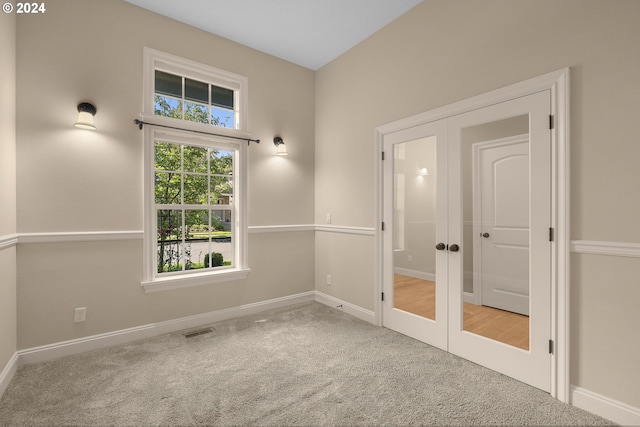 carpeted spare room with french doors, visible vents, and baseboards