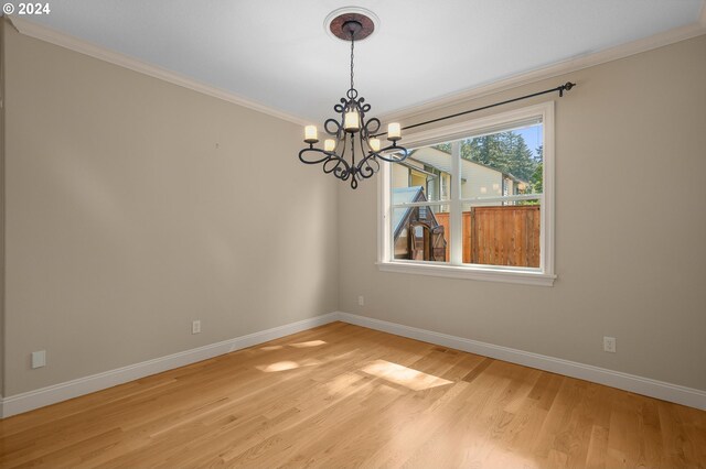 unfurnished room with a notable chandelier, crown molding, and light hardwood / wood-style floors