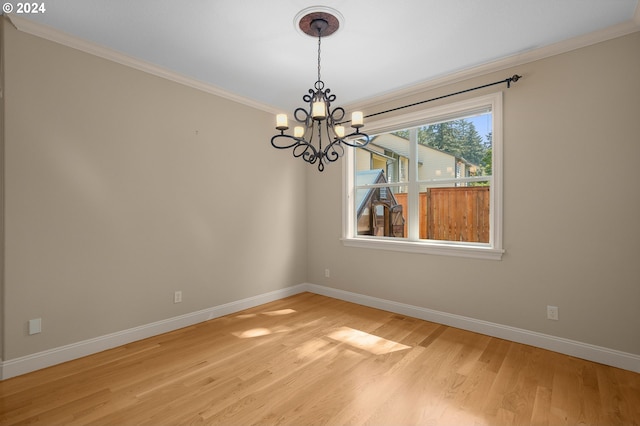 empty room featuring baseboards, light wood finished floors, an inviting chandelier, and crown molding