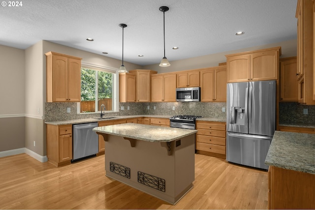 kitchen featuring light wood-type flooring, stainless steel appliances, pendant lighting, a center island, and sink