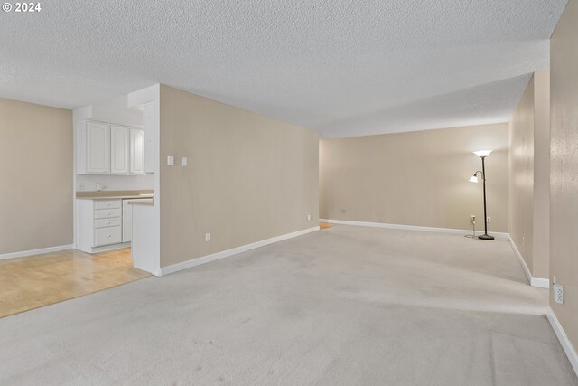 spare room featuring light colored carpet, a textured ceiling, and an AC wall unit