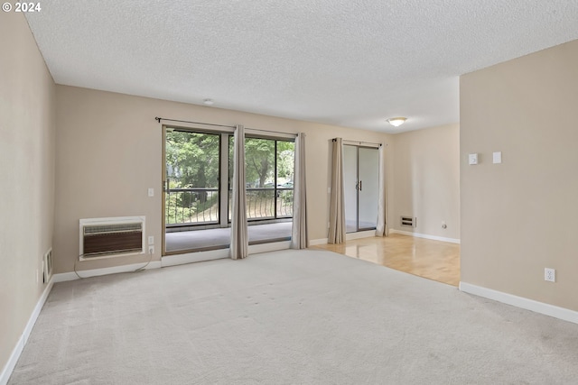 carpeted spare room with a textured ceiling and a wall mounted AC