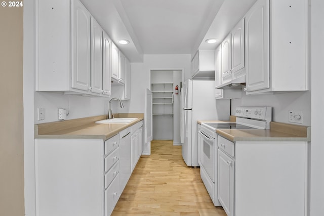 kitchen with white cabinets, light hardwood / wood-style floors, sink, and white appliances