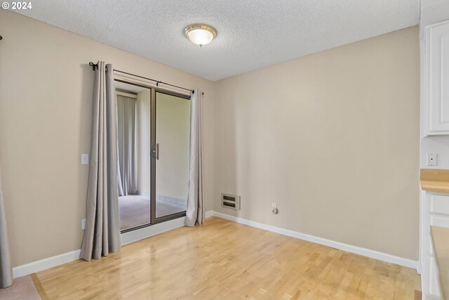 doorway to outside with light wood-type flooring and a textured ceiling