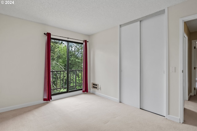 unfurnished bedroom with a closet, a textured ceiling, and light colored carpet