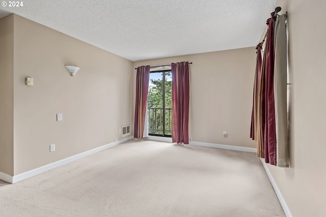 spare room featuring a textured ceiling and light colored carpet