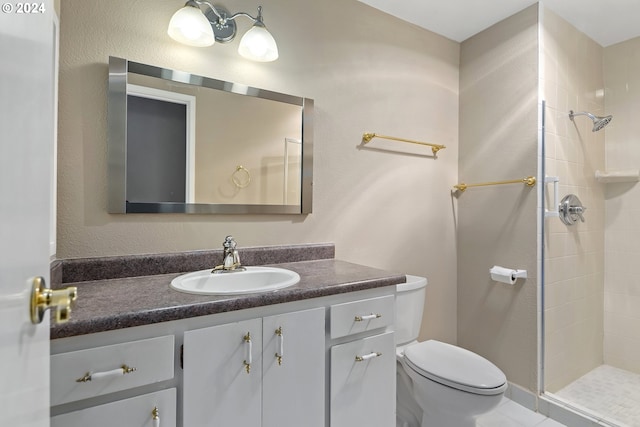 bathroom with tiled shower, vanity, and toilet