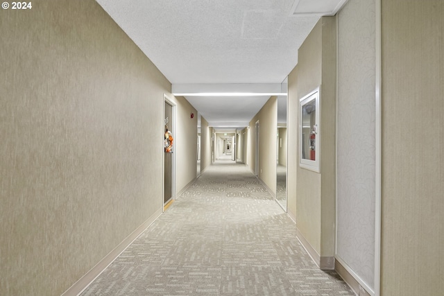 hallway featuring light colored carpet and a textured ceiling