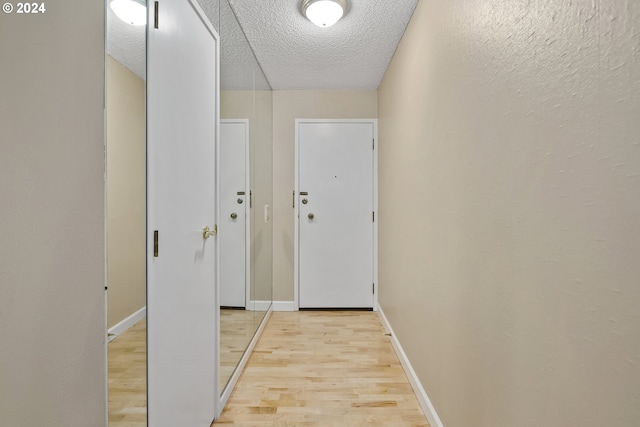 corridor featuring light hardwood / wood-style flooring and a textured ceiling