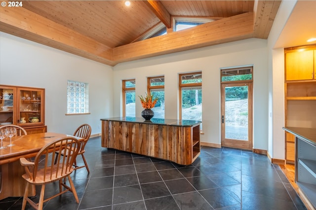 dining room featuring beam ceiling, wood ceiling, dark tile floors, and a healthy amount of sunlight