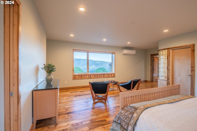 bedroom featuring light hardwood / wood-style flooring, an AC wall unit, and a mountain view