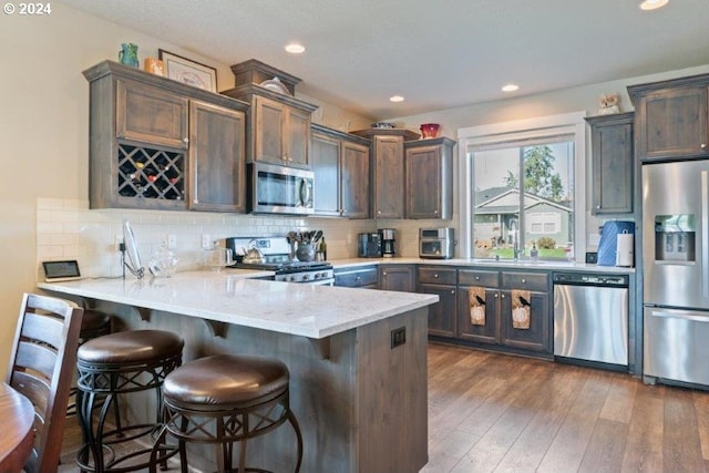 kitchen with stainless steel appliances, a sink, a peninsula, backsplash, and recessed lighting