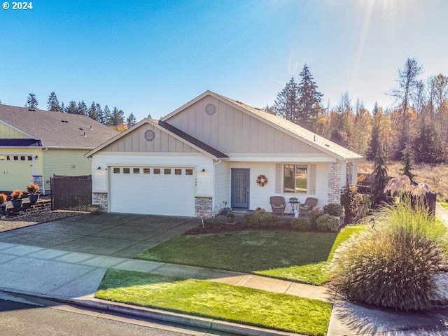 view of front of property with stone siding, an attached garage, driveway, a front yard, and board and batten siding