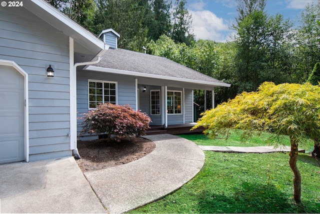 doorway to property featuring a porch and a lawn