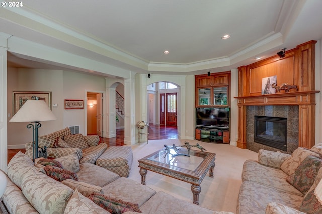 carpeted living room with ornamental molding, a fireplace, and a tray ceiling