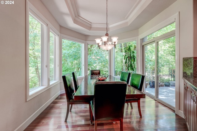 dining area with a raised ceiling, crown molding, hardwood / wood-style floors, and an inviting chandelier