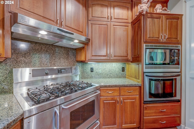 kitchen featuring light stone counters, stainless steel appliances, and tasteful backsplash