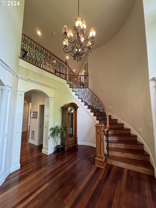 stairway featuring a notable chandelier, a high ceiling, and hardwood / wood-style flooring