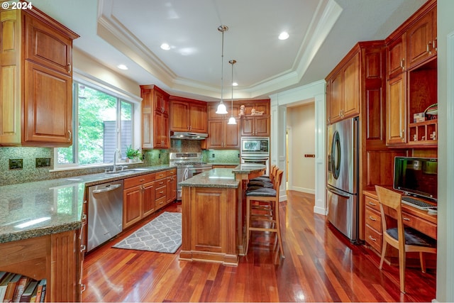 kitchen featuring a center island, stainless steel appliances, a raised ceiling, and hanging light fixtures