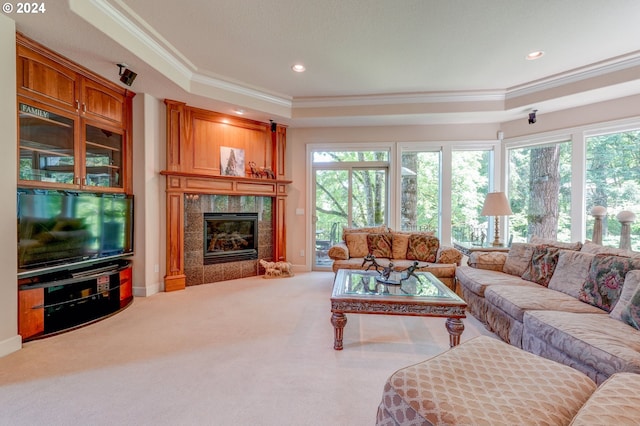 carpeted living room featuring a fireplace, a tray ceiling, and ornamental molding