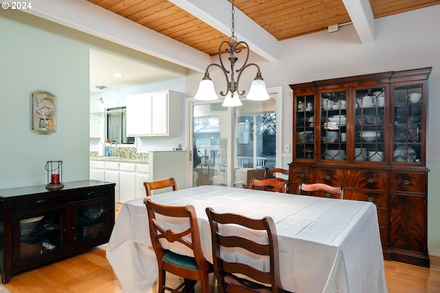 dining space featuring light hardwood / wood-style floors, beamed ceiling, and a notable chandelier