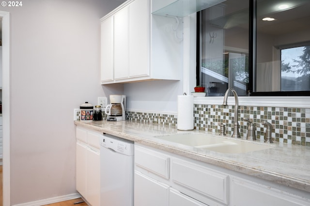 kitchen featuring light stone counters, dishwasher, white cabinets, sink, and backsplash