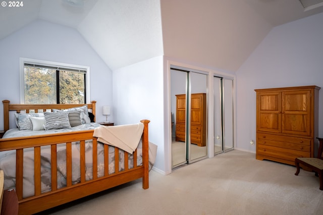 bedroom with light colored carpet, vaulted ceiling, and two closets