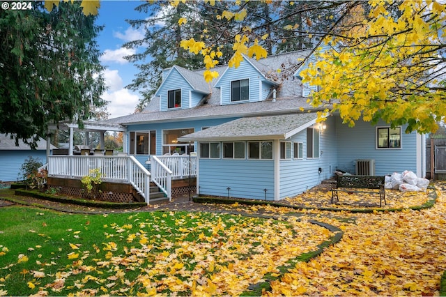 view of front of property featuring a sunroom, a front yard, and a deck