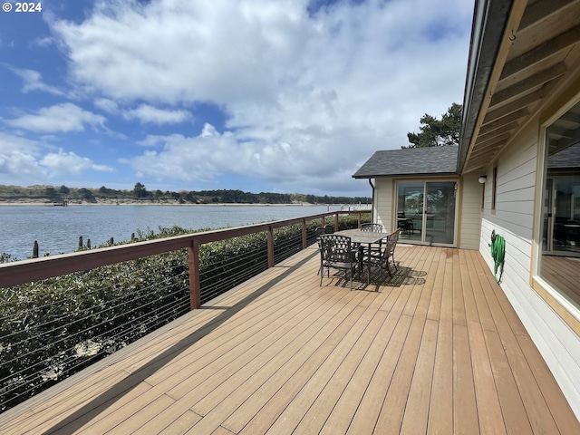 deck with a water view and outdoor dining space