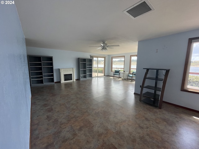 unfurnished living room featuring ceiling fan, a fireplace, visible vents, and baseboards