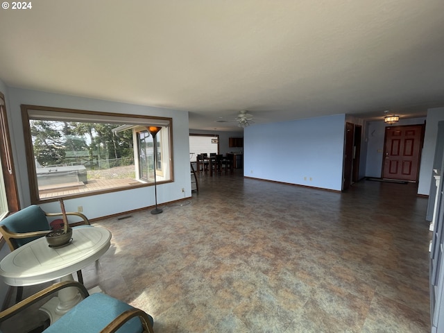 living area with baseboards and ceiling fan