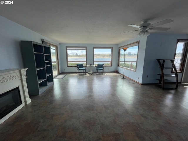 unfurnished living room with a glass covered fireplace, plenty of natural light, and baseboards