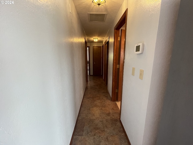 hall featuring visible vents and a textured wall