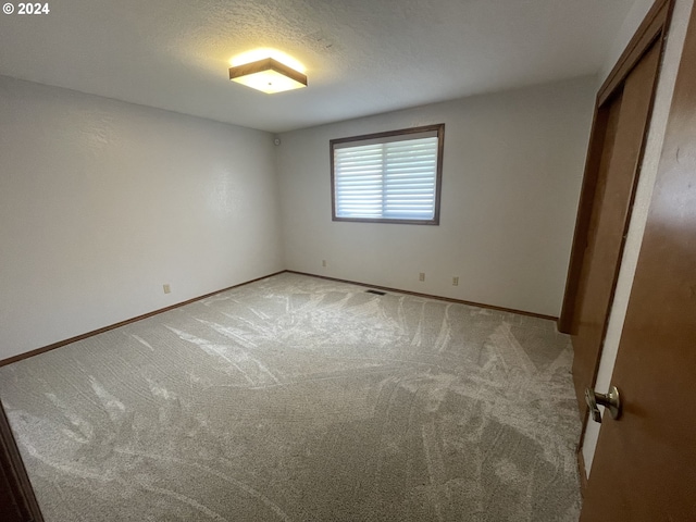 unfurnished bedroom with light carpet, visible vents, a textured ceiling, and baseboards