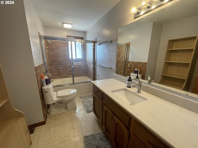 bathroom with vanity, bath / shower combo with glass door, a textured ceiling, tile patterned floors, and toilet