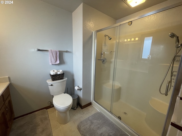 full bathroom with vanity, baseboards, tile patterned flooring, a shower stall, and toilet