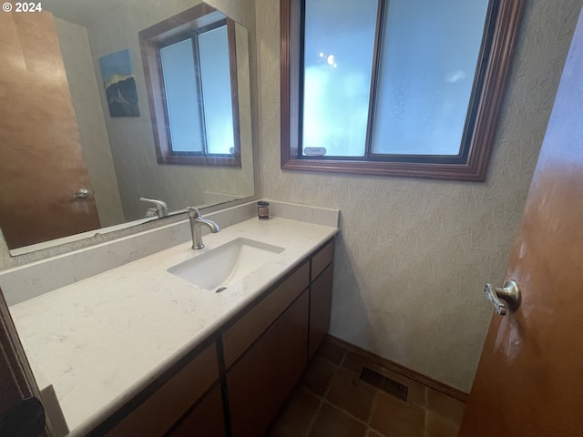 bathroom with vanity, a textured wall, visible vents, and tile patterned flooring