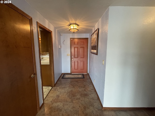 doorway with a textured wall and carpet floors