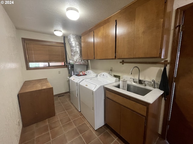 clothes washing area with dark tile patterned flooring, cabinet space, a sink, a textured ceiling, and independent washer and dryer