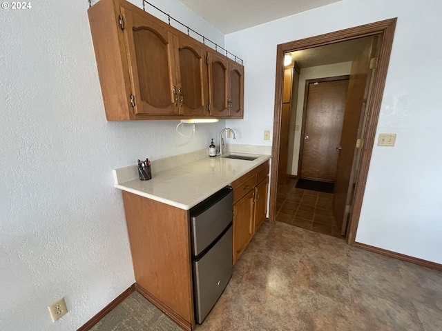 kitchen featuring brown cabinetry, dishwasher, light countertops, and a sink