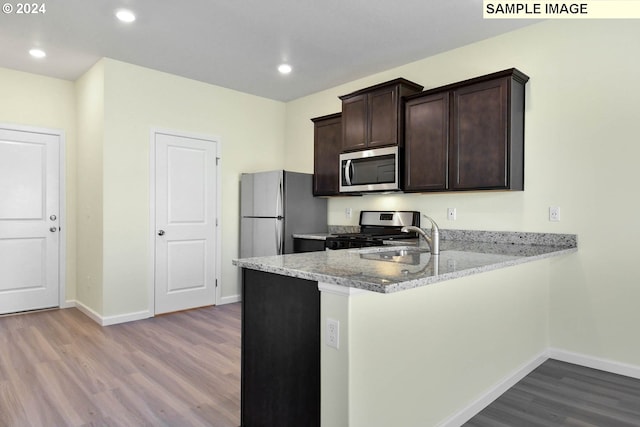 kitchen featuring light stone counters, kitchen peninsula, stainless steel appliances, light wood-type flooring, and dark brown cabinetry