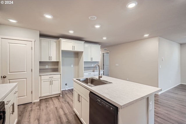 kitchen featuring sink, light hardwood / wood-style flooring, black dishwasher, white cabinetry, and an island with sink