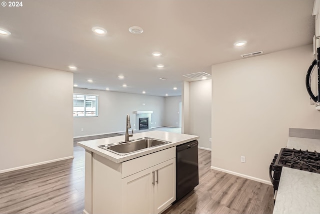 kitchen with dishwasher, light wood-type flooring, white cabinets, and an island with sink